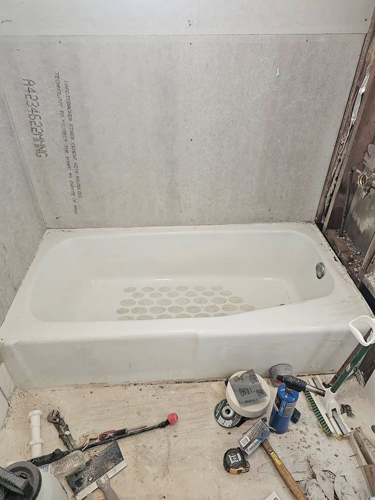 Bathroom before: bare tub and backer board