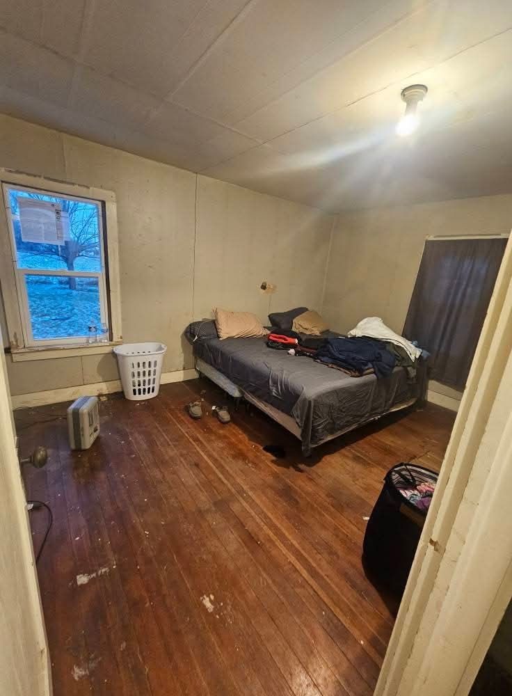 Bedroom before: worn floors, damaged walls and bare ceiling
